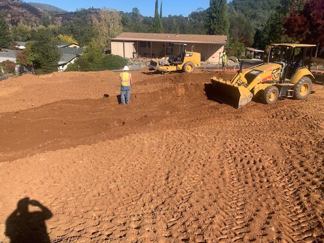 A man with a bulldozer working on a dirt yard.
