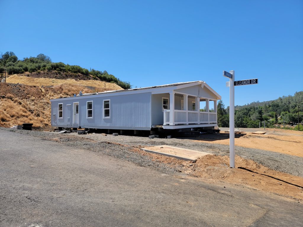 A mobile home is being built on a dirt road.