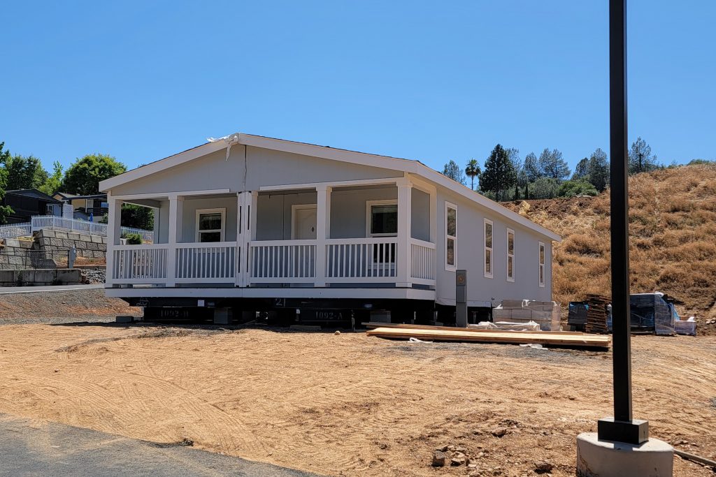 A mobile home is being built on a dirt lot.