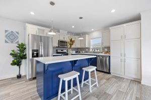 A Grand Opening kitchen with a blue island and stools.