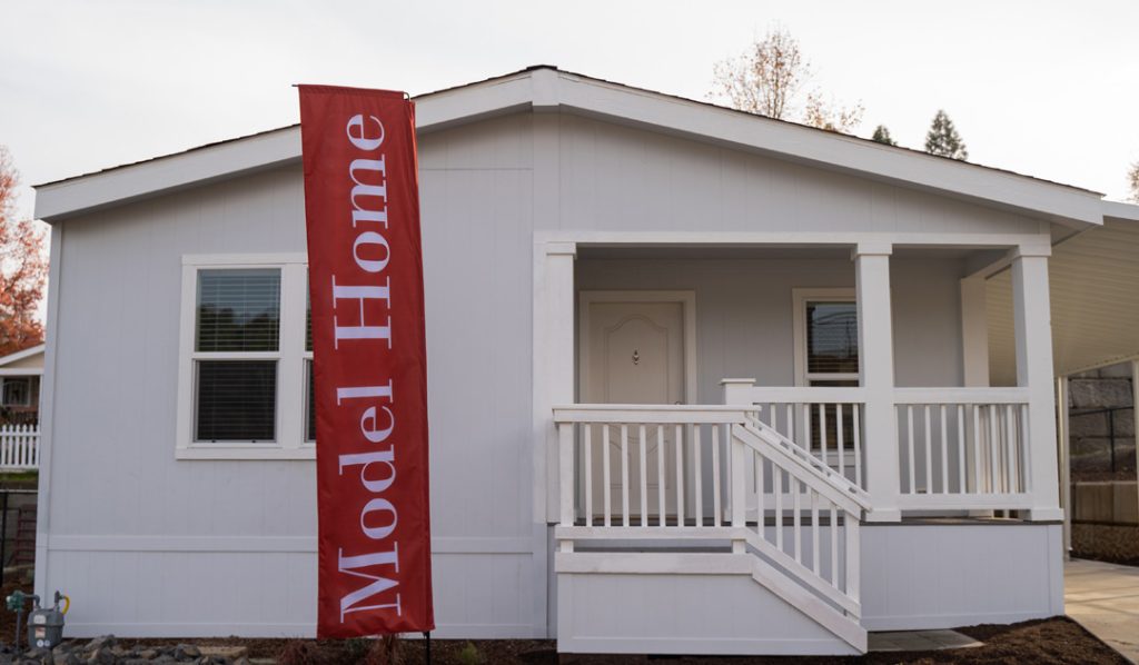 A model home with a red banner on the front porch.
