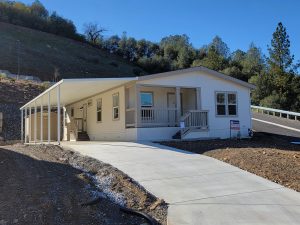 A mobile home is being built on a hillside for an open house.