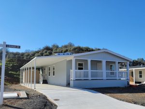 A mobile home is being built on a lot, with an open house.
