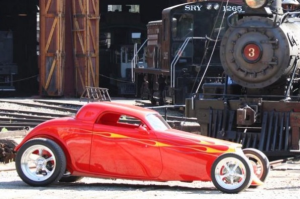 A red hot rod is parked next to a train in Tuolumne County.
