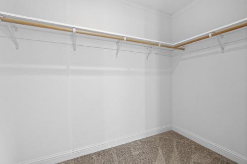 An empty closet with white walls and a wooden rail.