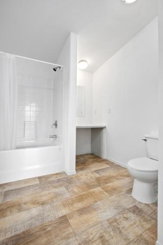A bathroom with white walls and wood floors.