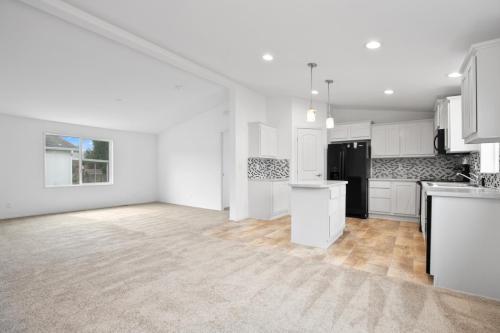 An empty kitchen with white cabinets and carpet.