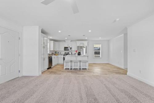 A white kitchen with carpet and a ceiling fan.