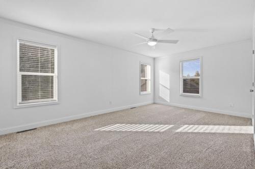 An empty room with white walls and a ceiling fan.