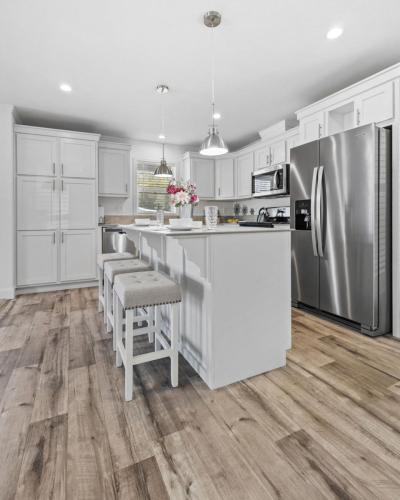 A white kitchen with wood floors and stainless steel appliances.