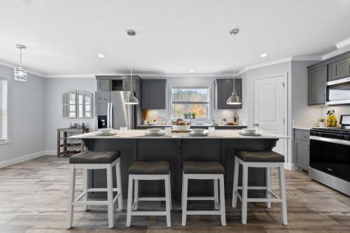A kitchen with gray cabinets and a bar stools.