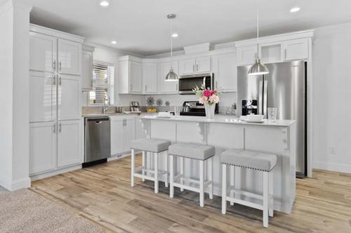 A white kitchen with wood floors and stools.