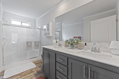 A bathroom with gray cabinets and a walk in shower.